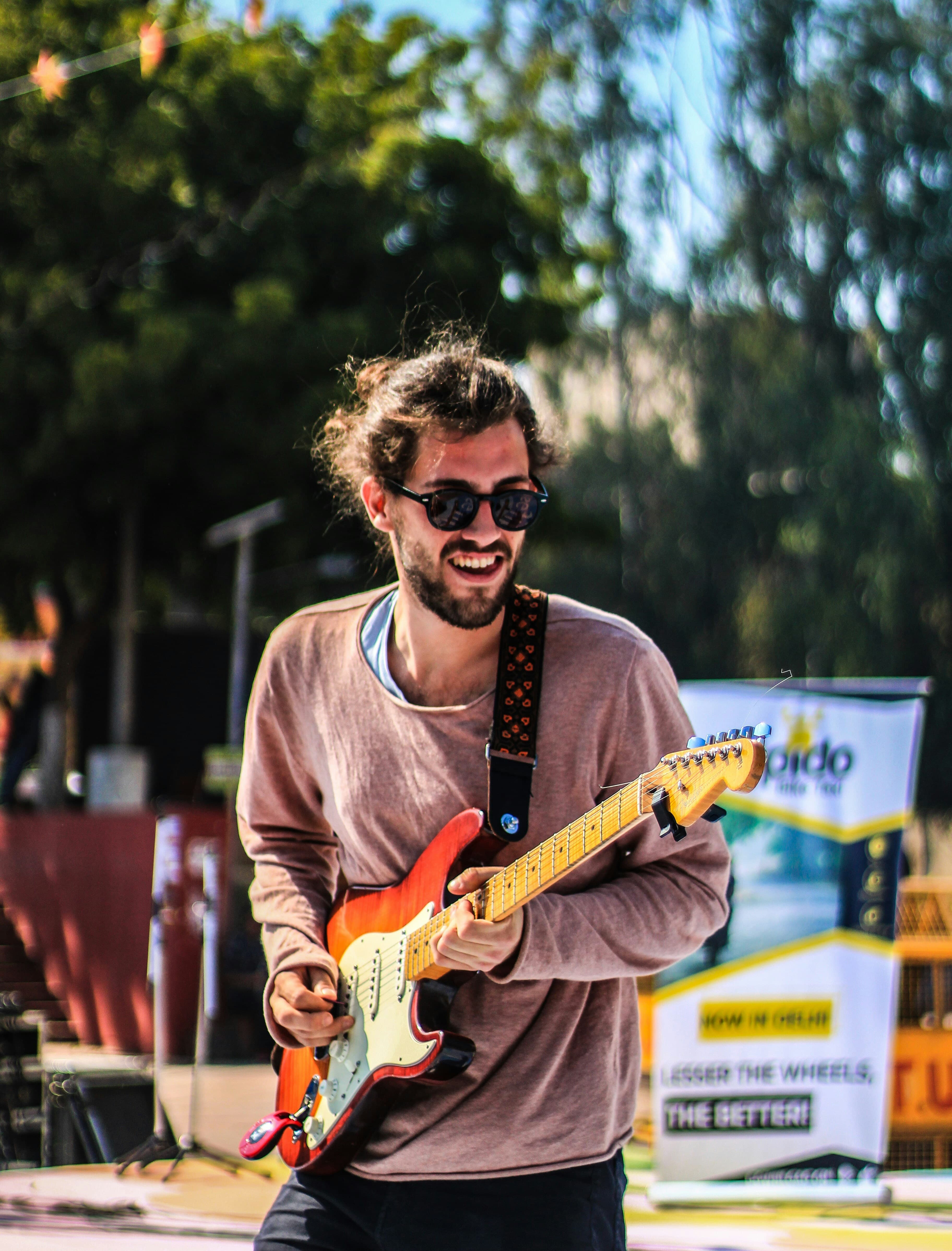 Aluno tocando guitarra elétrica ao vivo, sorrindo